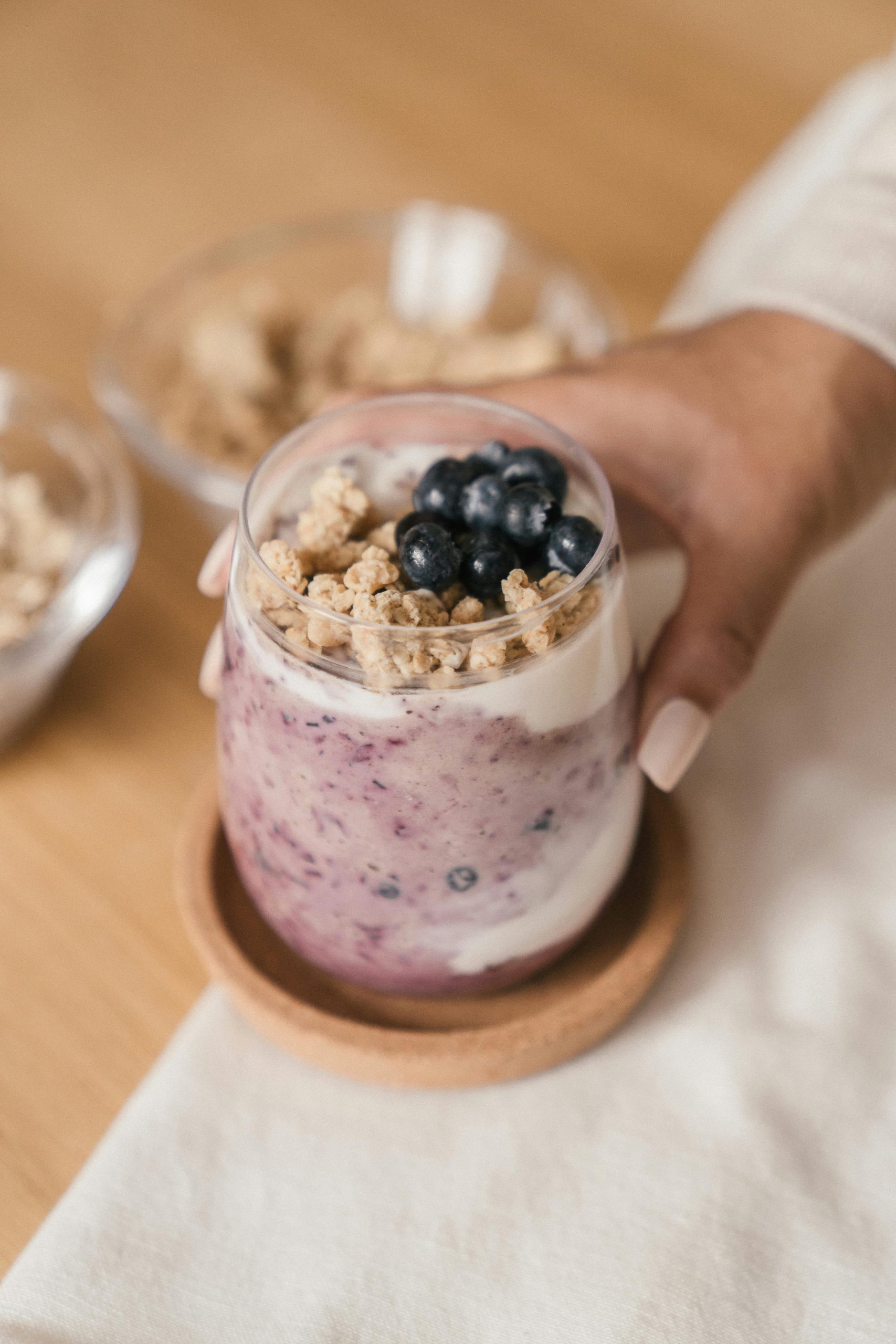 Hand holding a blueberry yogurt parfait with granola, perfect healthy breakfast.